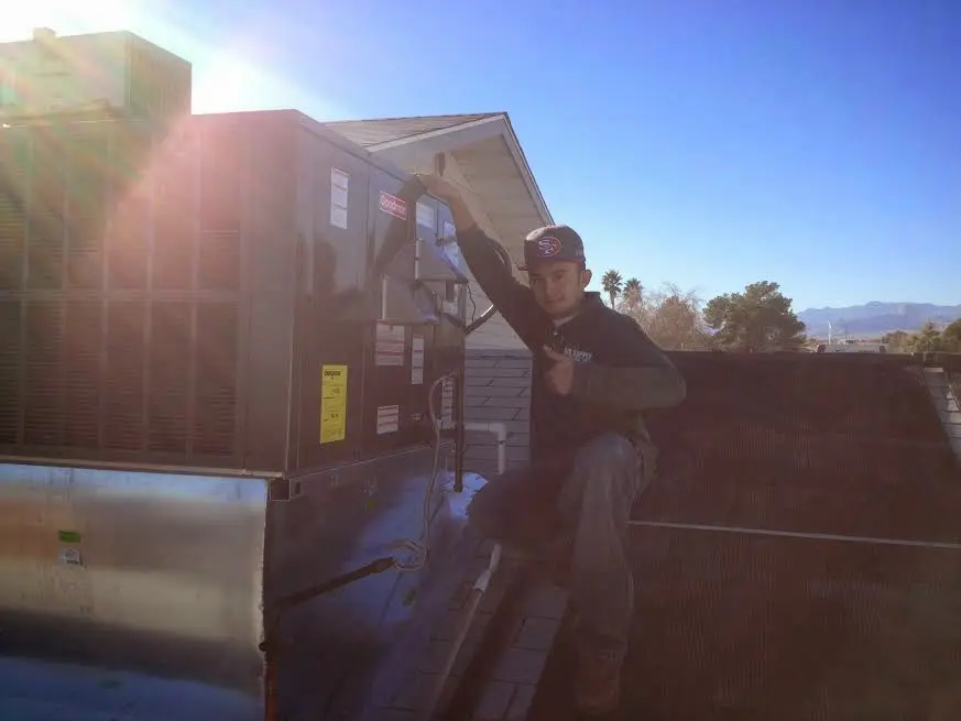 HVAC technician performing Air Duct Cleaning on a rooftop unit in Santa Ana